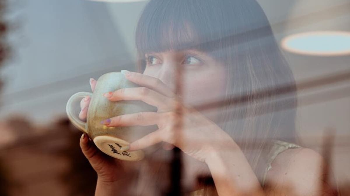 Femme buvant du café à travers la vitre